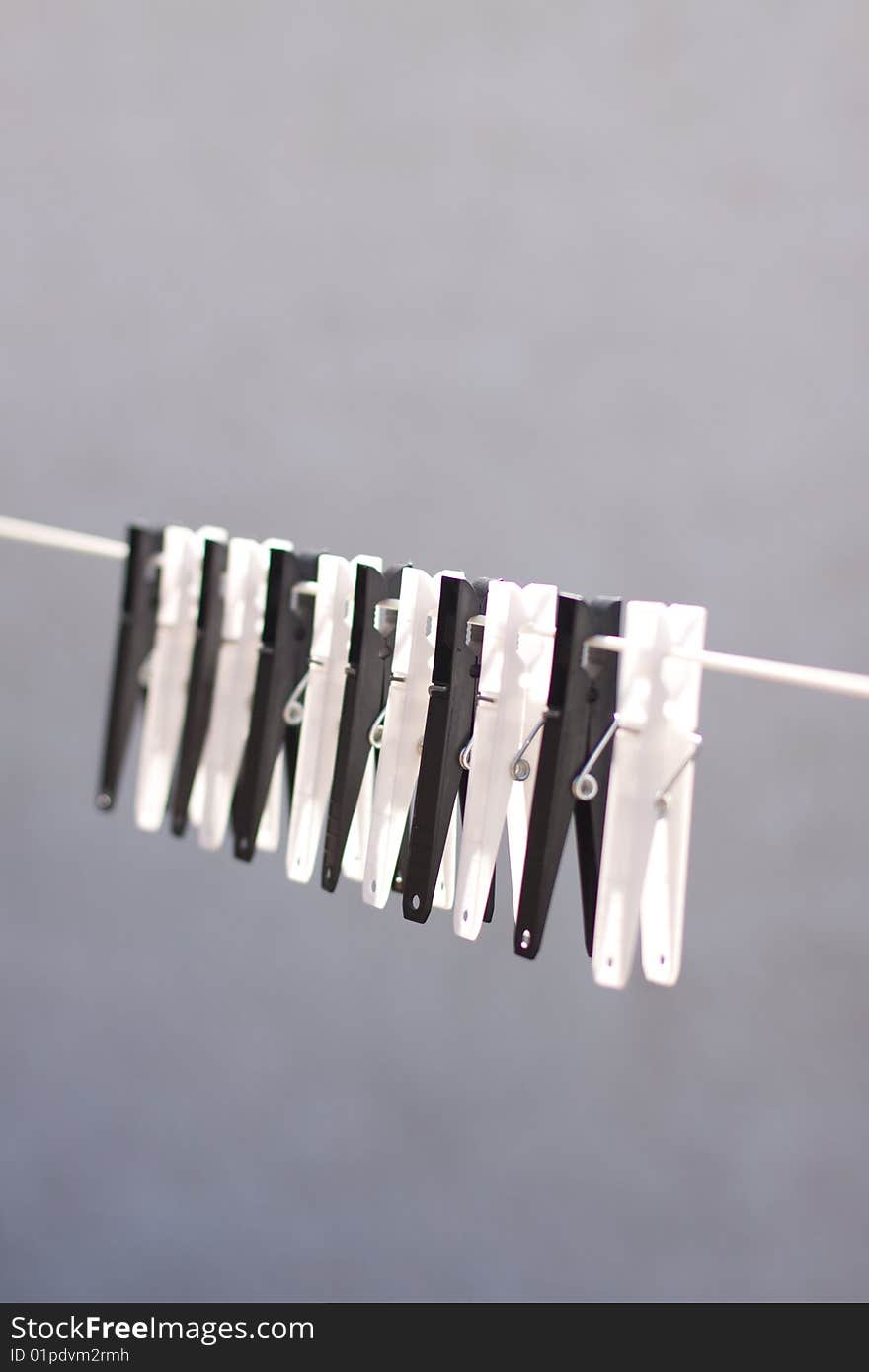 A row of black and white clothes pegs on a line with a blue sky background