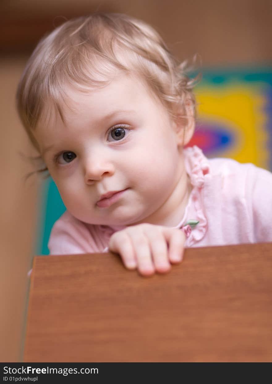 Little girl looking at you out of a table - shallow DOF