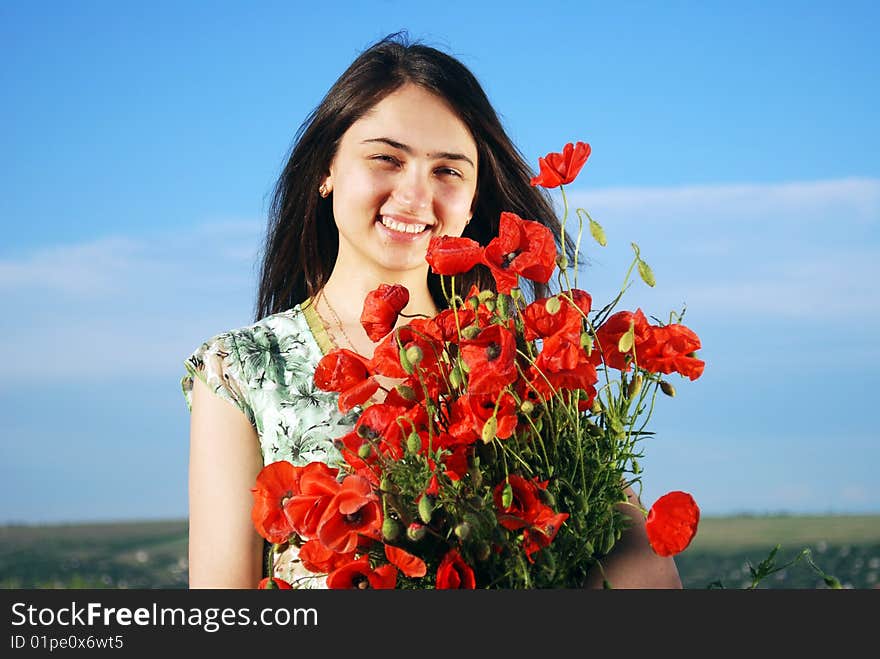 A beautiful girl standing on a field filled with red poppies. A beautiful girl standing on a field filled with red poppies