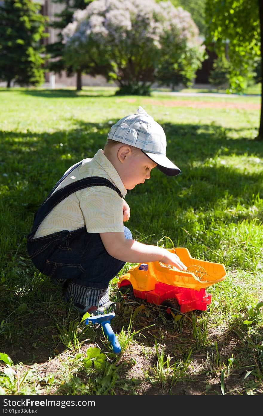 Boy plays the toy car on a green grass