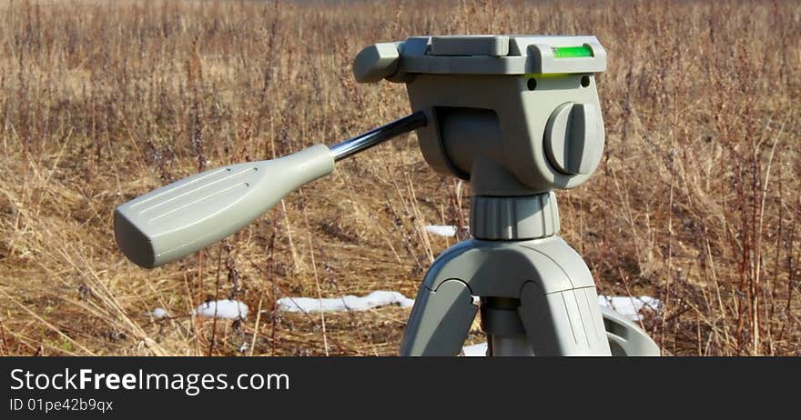 Tripod head in field with melting snow.