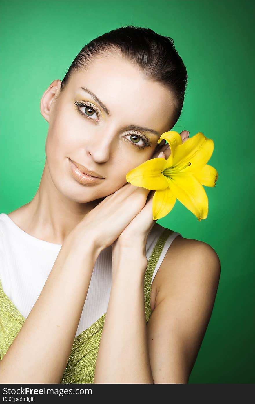 Portrait of young woman with yellow flowers on the green backdround