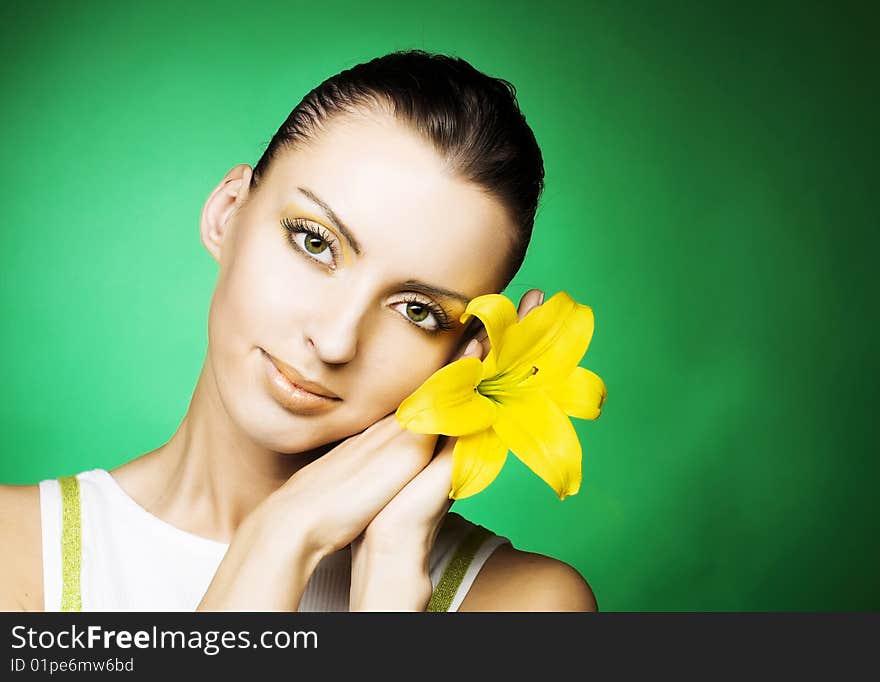 Portrait of young woman with yellow flowers on the green backdround