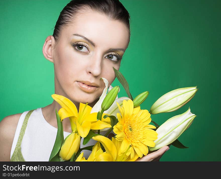 Portrait of young woman with yellow flowers on the green backdround