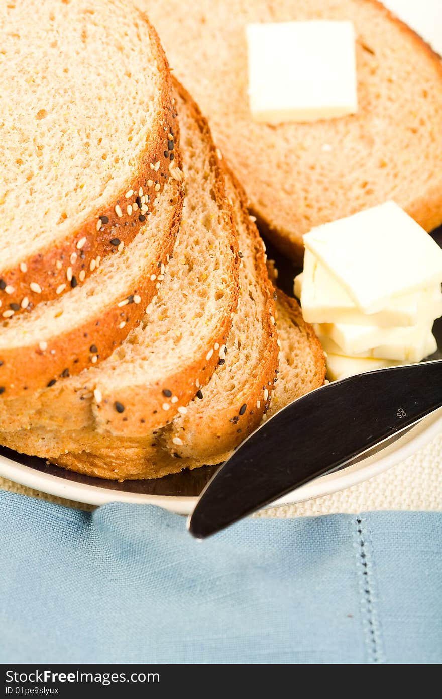 Multi-grain wheat  Bread stacked on blue plate with butter and knife. Multi-grain wheat  Bread stacked on blue plate with butter and knife