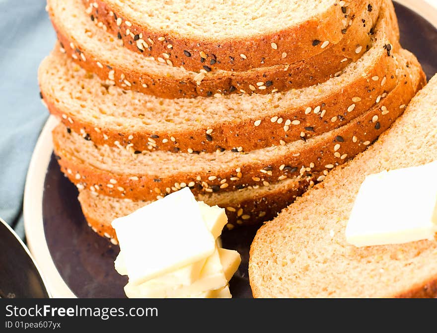 Multi-grain wheat  Bread stacked on blue plate with butter and knife. Multi-grain wheat  Bread stacked on blue plate with butter and knife