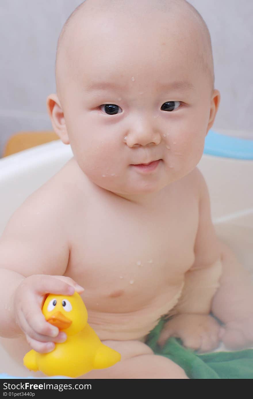 Asian baby boy holding  a yellow plastic duck in bath. Asian baby boy holding  a yellow plastic duck in bath