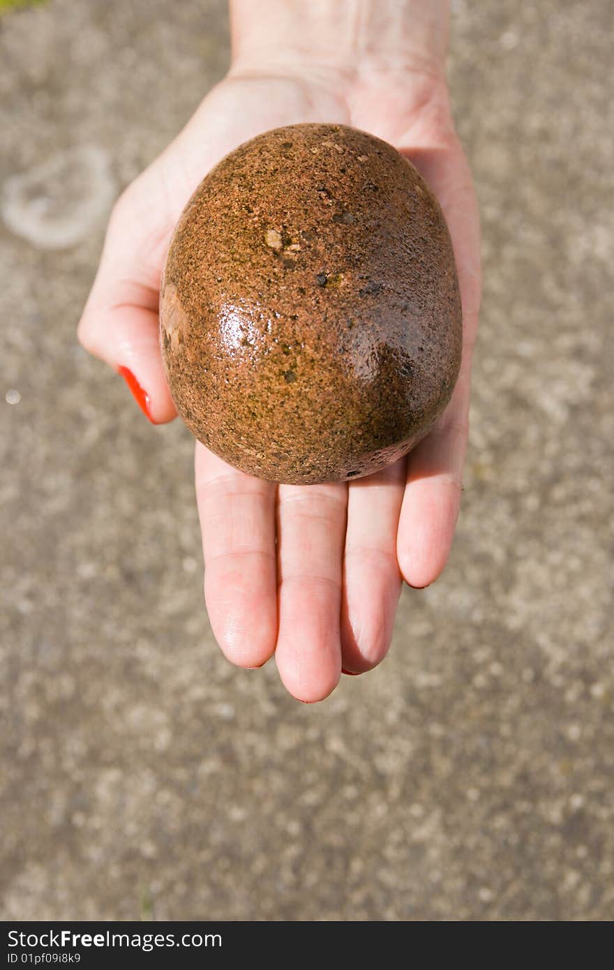 Single hand holding a stone out stretched with a stone background. Single hand holding a stone out stretched with a stone background