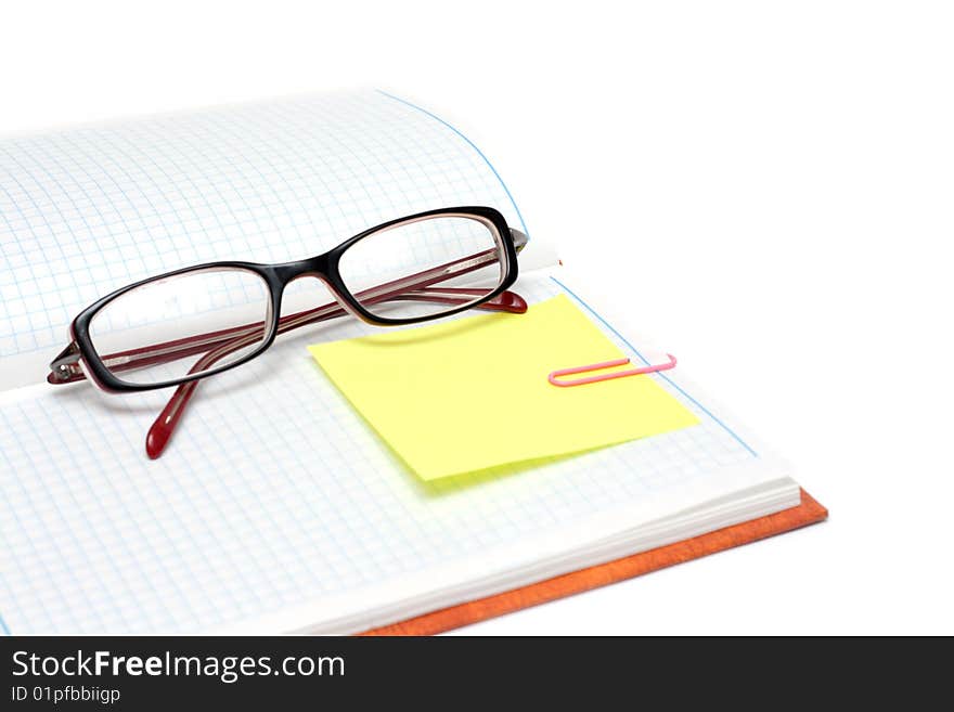 Spectacles on note pad with yellow bookmark and rose staple