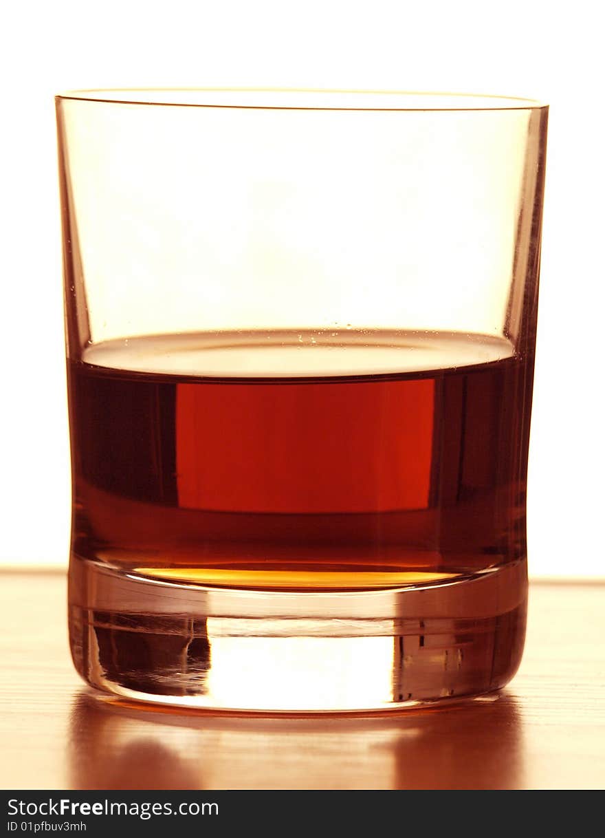 Color photo of a glass of whiskey on a wooden table