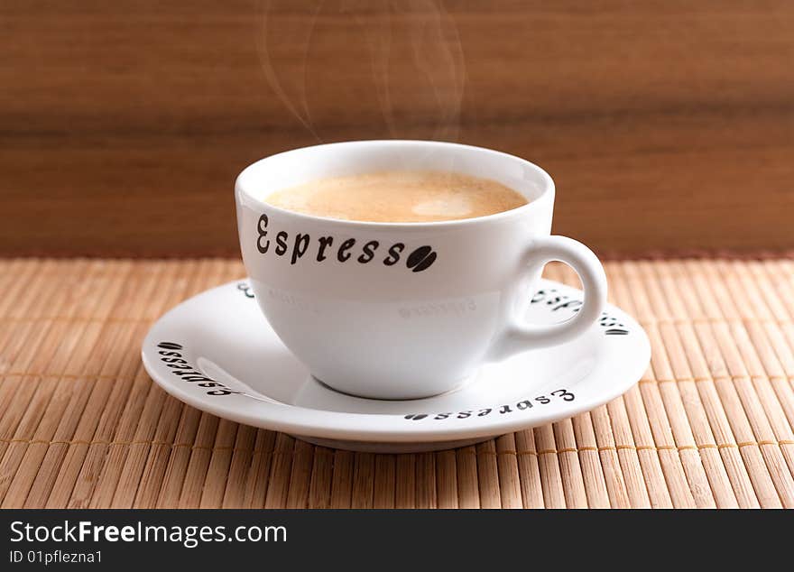 A cup of fresh coffee in front of a wooden background