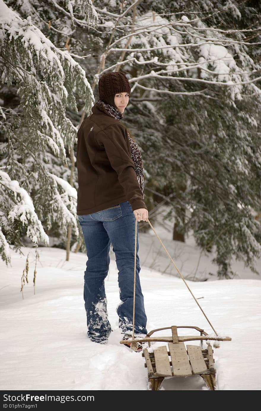 Beautiful woman pulling sled through snow