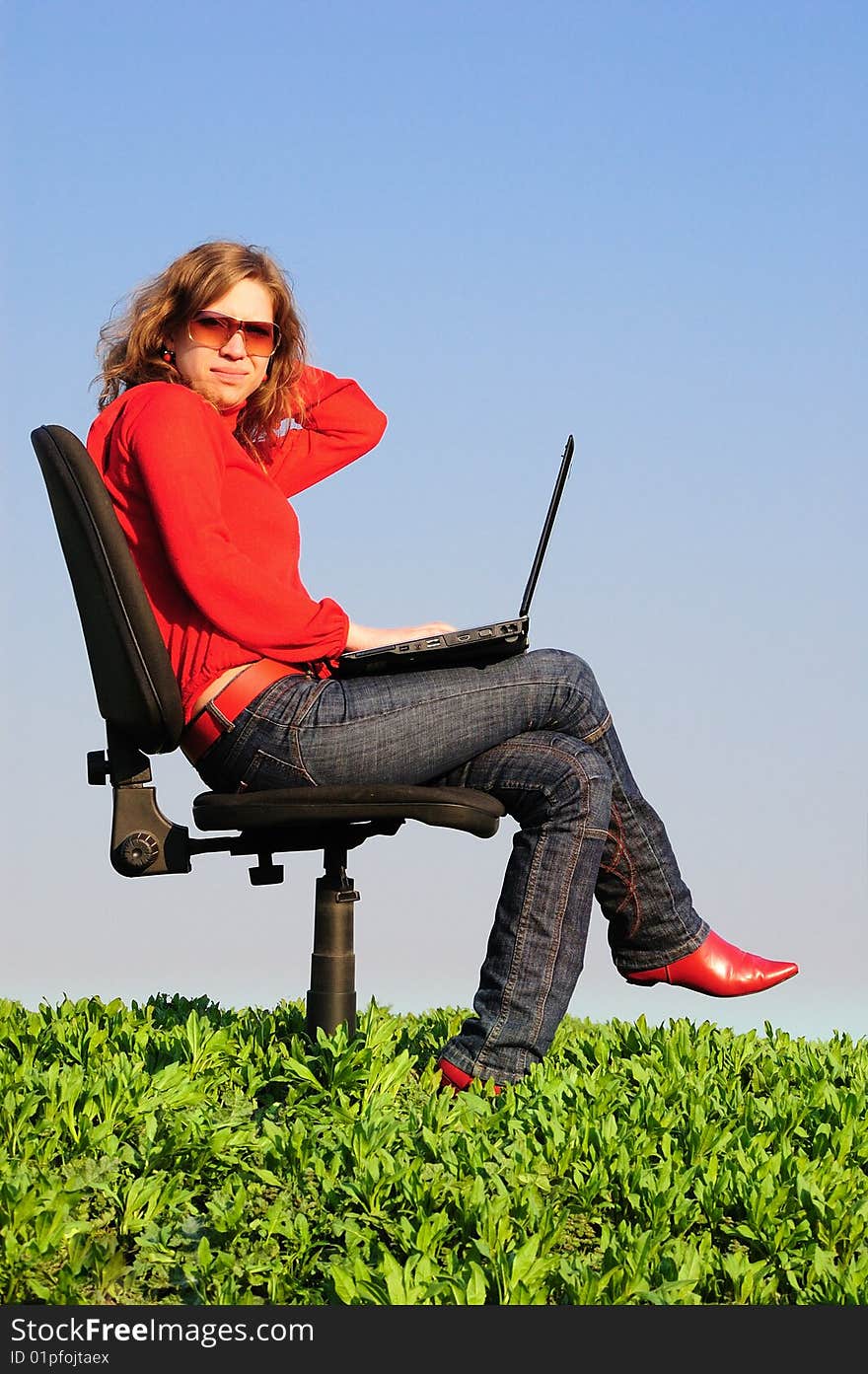 The beautiful girl in armchair with the laptop. Spring. Field. The beautiful girl in armchair with the laptop. Spring. Field