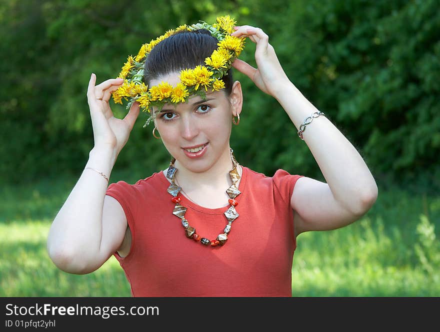 The young woman with a wreath from dandelions on a head. The young woman with a wreath from dandelions on a head