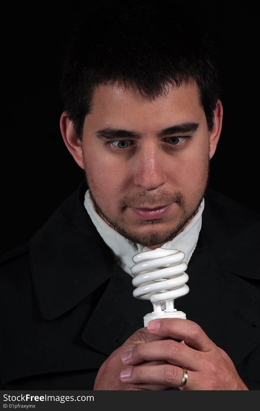 Male portrait staring at new light bulb isolated on black background