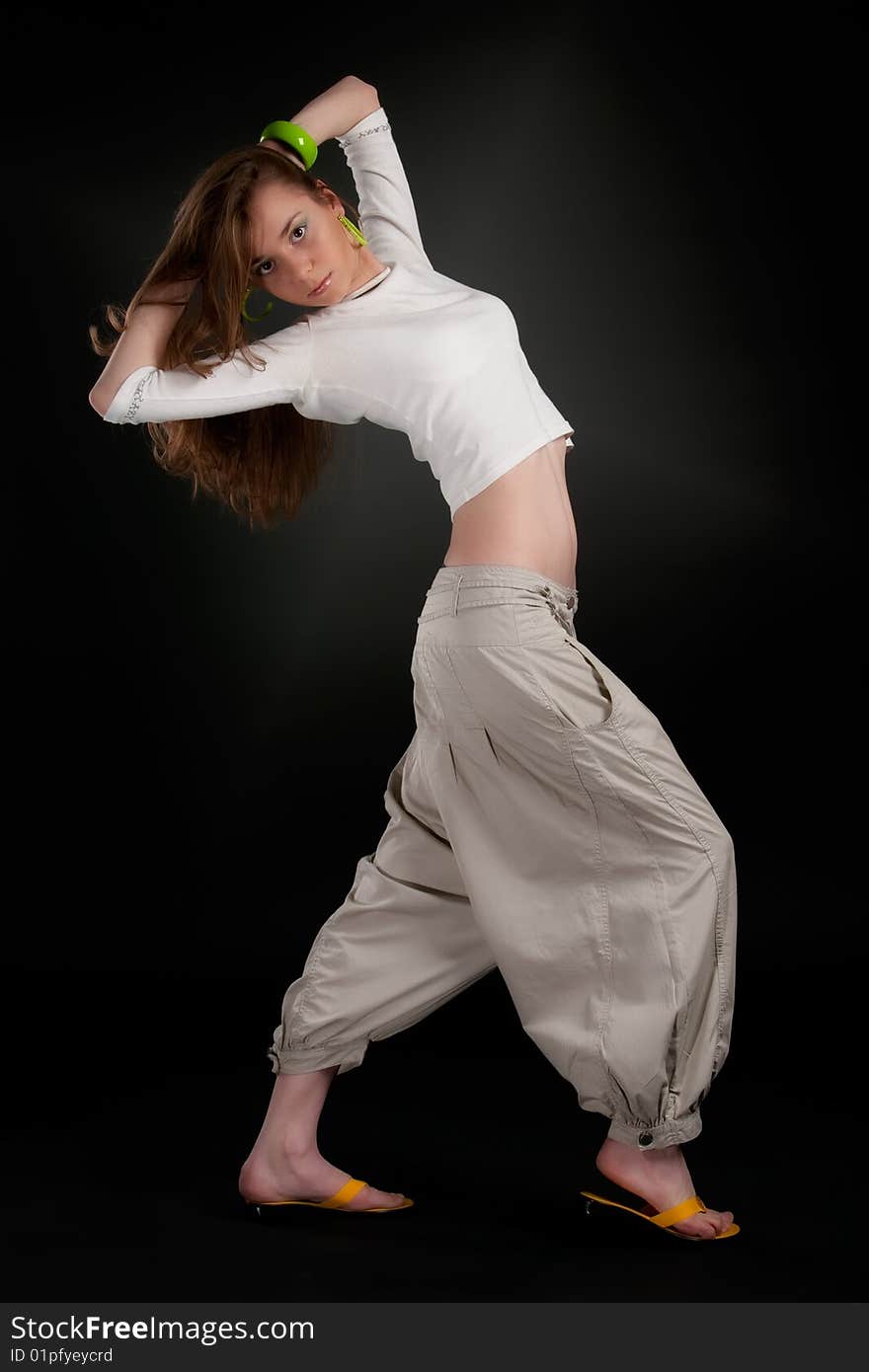 Dancing pose of young girl against a black background with aureole. Dancing pose of young girl against a black background with aureole