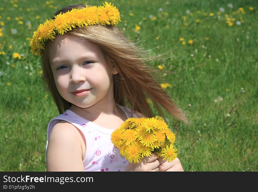 The little girl on a meadow with a bouquet of dandelions