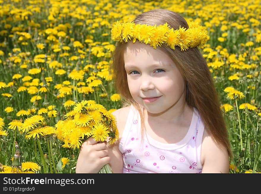 The little girl on a meadow with a bouquet of dandelions