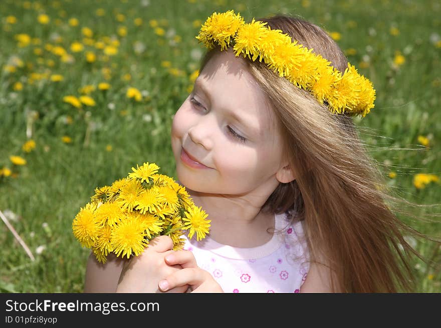 The little girl on a meadow with a bouquet of dandelions