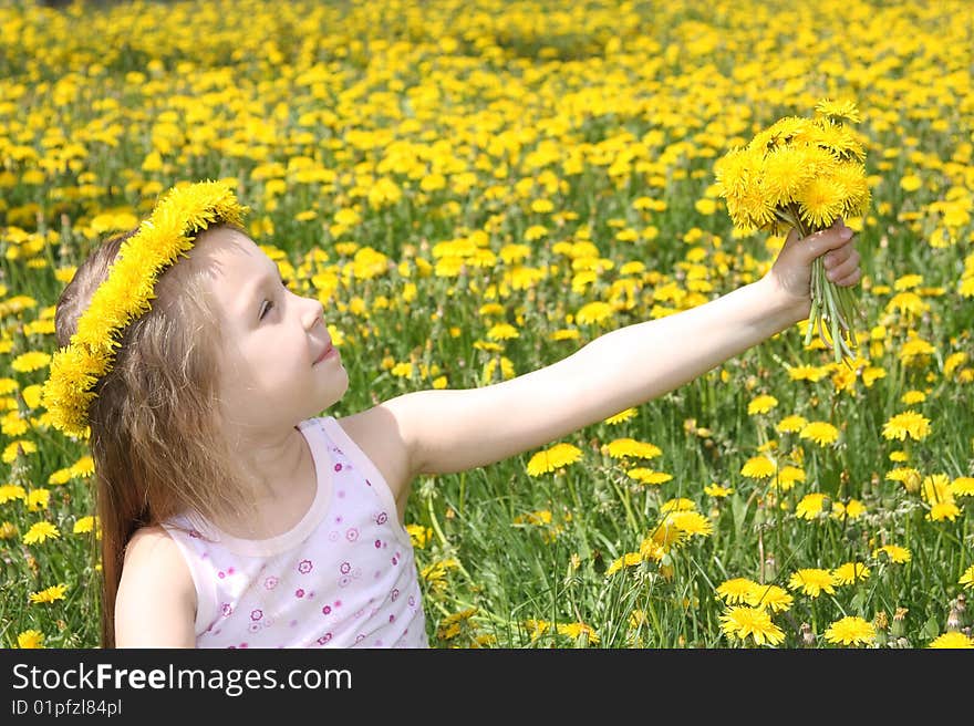 The little girl on a meadow with a bouquet of dandelions