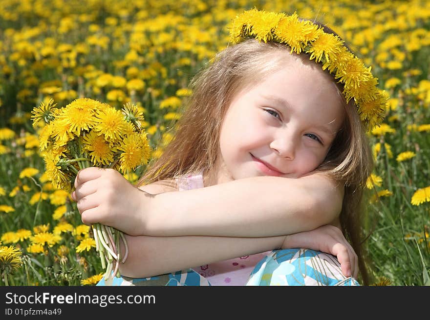 The little girl on a meadow with a bouquet of dandelions