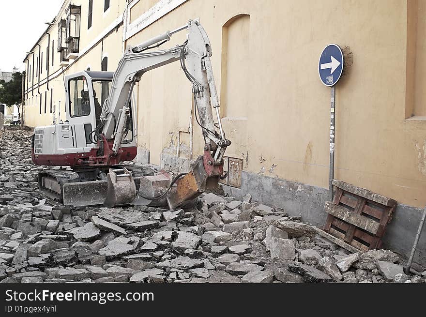 Excavating machine destroying the asphalt of a street. Excavating machine destroying the asphalt of a street