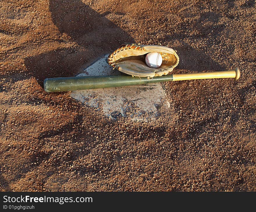 This bat,glove and ball are waiting on home base for the big game,with crushed shale for ground cover there is no mud on a rainy day. This bat,glove and ball are waiting on home base for the big game,with crushed shale for ground cover there is no mud on a rainy day.