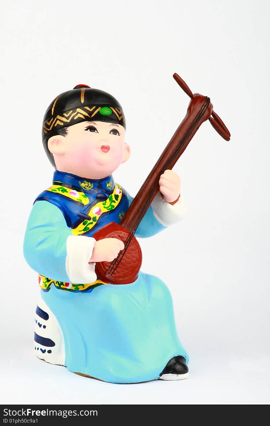 This is a clay figure of an Asian boy in traditional robe playing a stringed instrument. This is a clay figure of an Asian boy in traditional robe playing a stringed instrument.