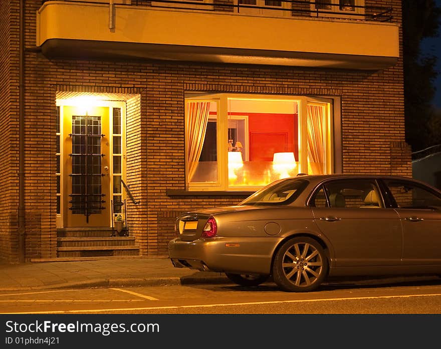 A Jaguar car parked in front of a house at night after a long day of work. A Jaguar car parked in front of a house at night after a long day of work