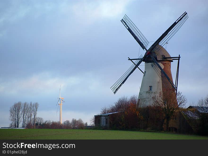 Morning light, traditional windmill in the foreground and modern windmill generators on a background. Morning light, traditional windmill in the foreground and modern windmill generators on a background