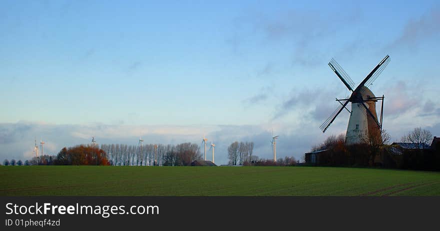 Morning light, traditional windmill in the foreground and modern windmill generators on a background. Morning light, traditional windmill in the foreground and modern windmill generators on a background