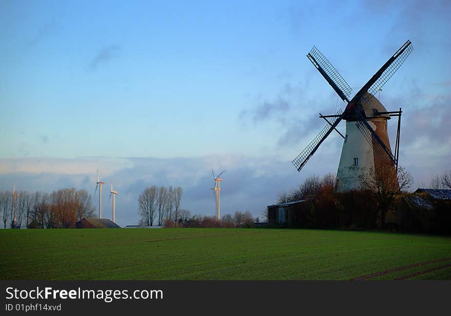 Morning light, traditional windmill in the foreground and modern windmill generators on a background. Morning light, traditional windmill in the foreground and modern windmill generators on a background