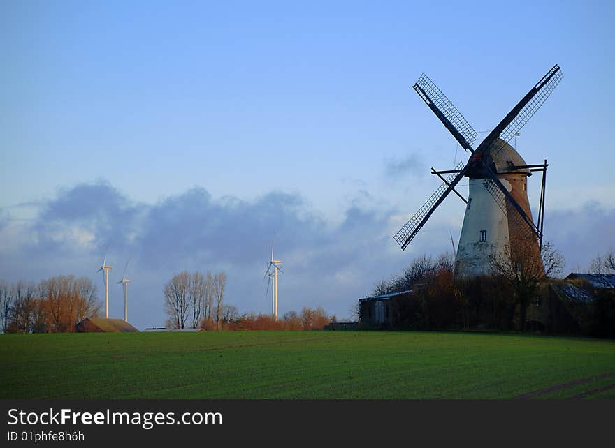 Morning light, traditional windmill in the foreground and modern windmill generators on a background. Morning light, traditional windmill in the foreground and modern windmill generators on a background