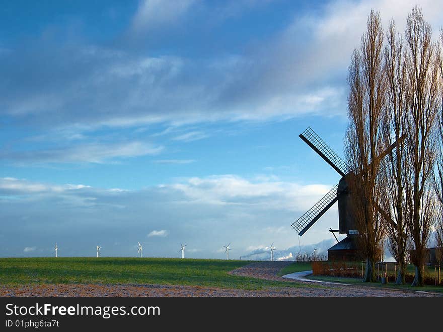 Traditional windmill in the foreground and modern windmill generators on a background. Traditional windmill in the foreground and modern windmill generators on a background