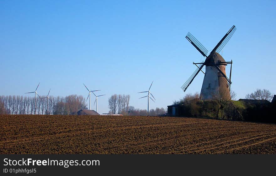 Morning light, traditional windmill in the foreground and modern windmill generators on a background. Morning light, traditional windmill in the foreground and modern windmill generators on a background