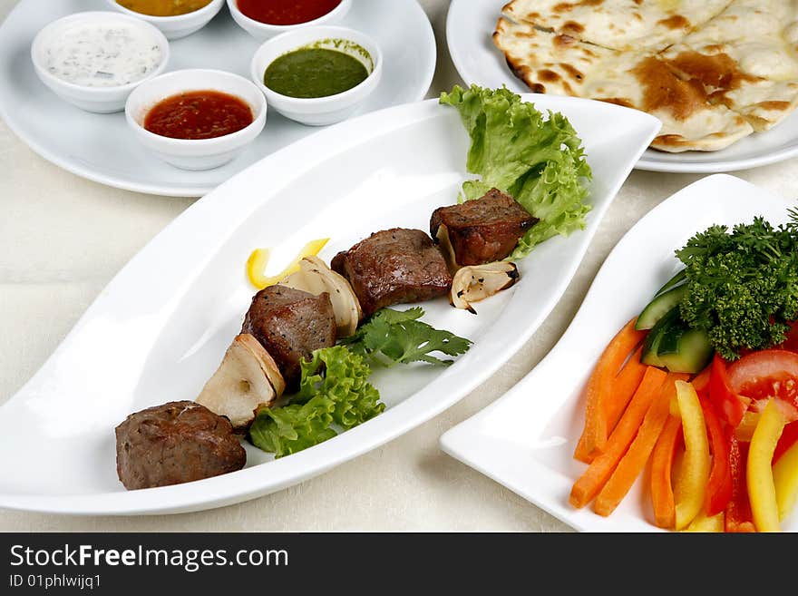 Appetizing shish kebab with tomatoes and greens