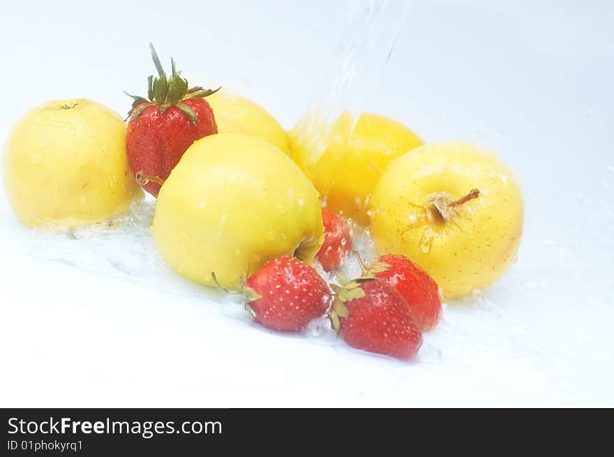 Ripe apples and strawberries under water splash