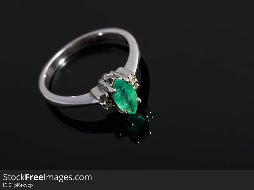 Silver ring with green stone on dark, reflective background. Silver ring with green stone on dark, reflective background