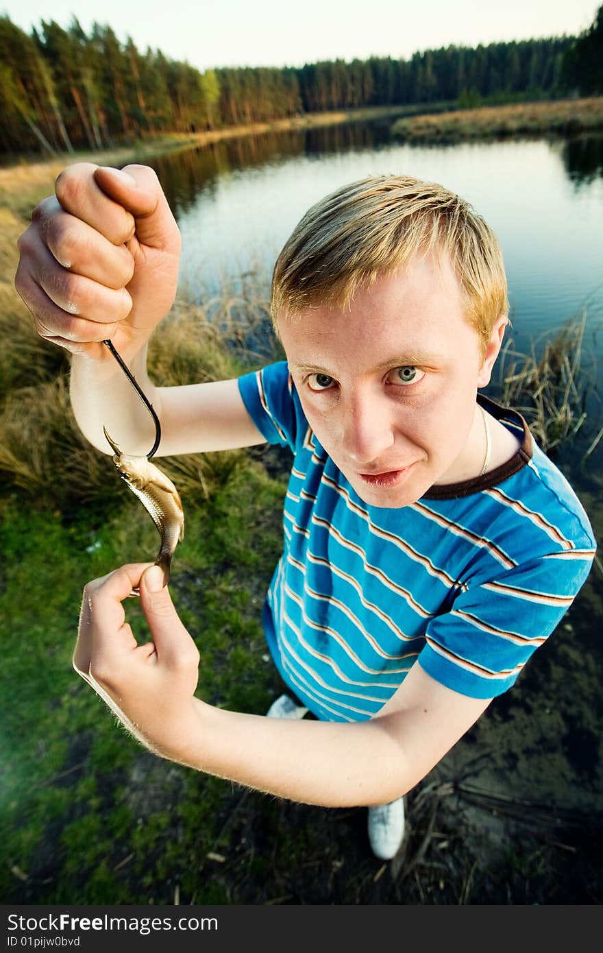 A guy on a river bank demonstrating  his catch. A guy on a river bank demonstrating  his catch