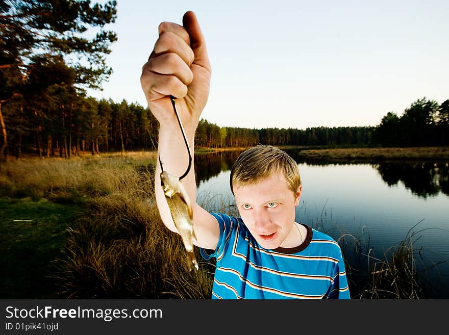 A guy on a river bank demonstrating  his catch. A guy on a river bank demonstrating  his catch