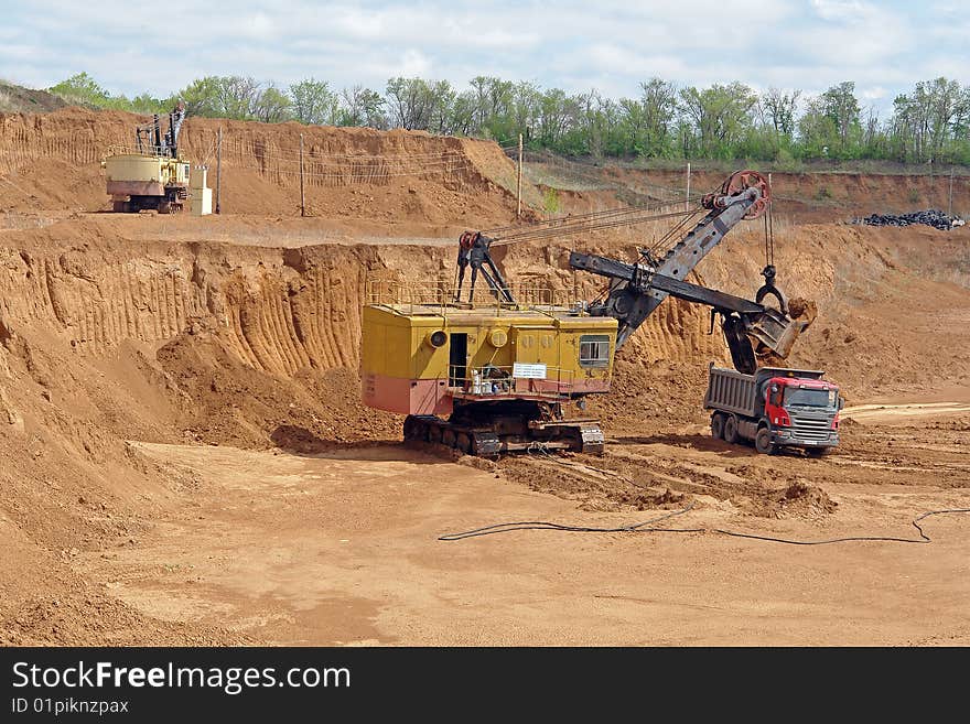 The excavator is loading rock into the truck. The excavator is loading rock into the truck