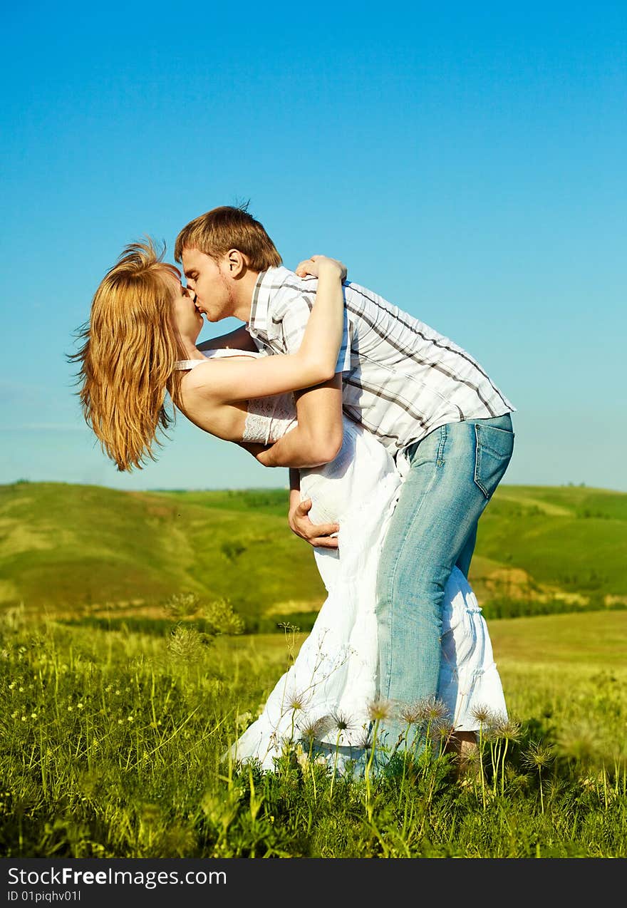 Happy young loving couple kissing outdoor in summertime. Happy young loving couple kissing outdoor in summertime