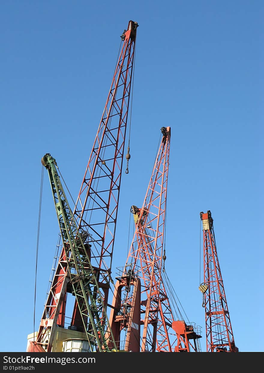 Several cranes in a harbor on blue sky