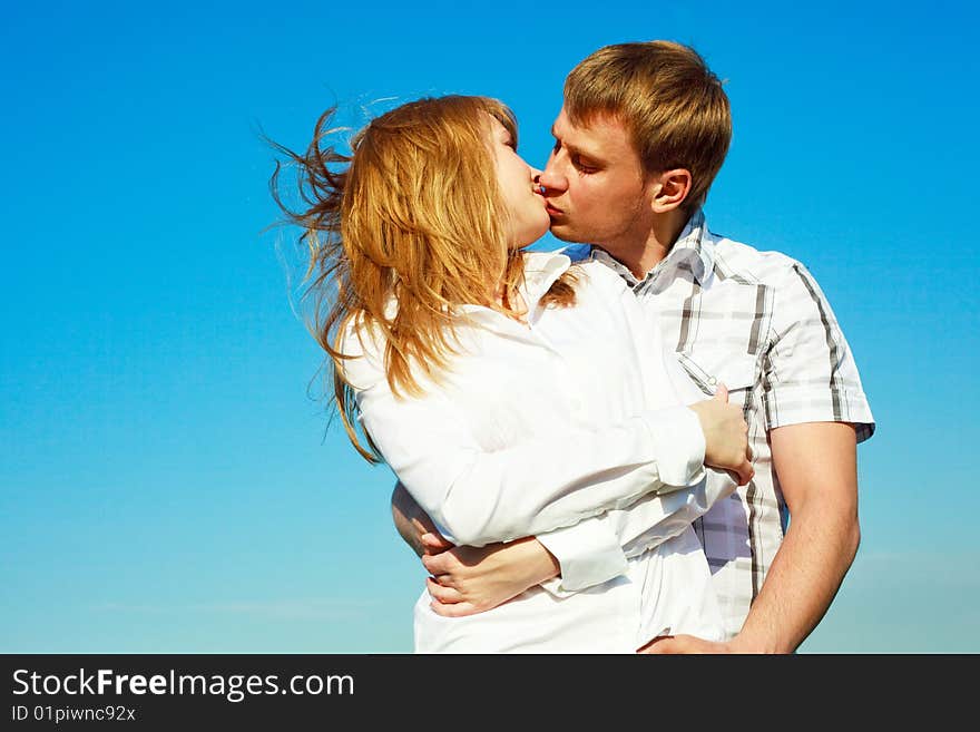 Happy young loving couple kissing outdoor in summertime. Happy young loving couple kissing outdoor in summertime