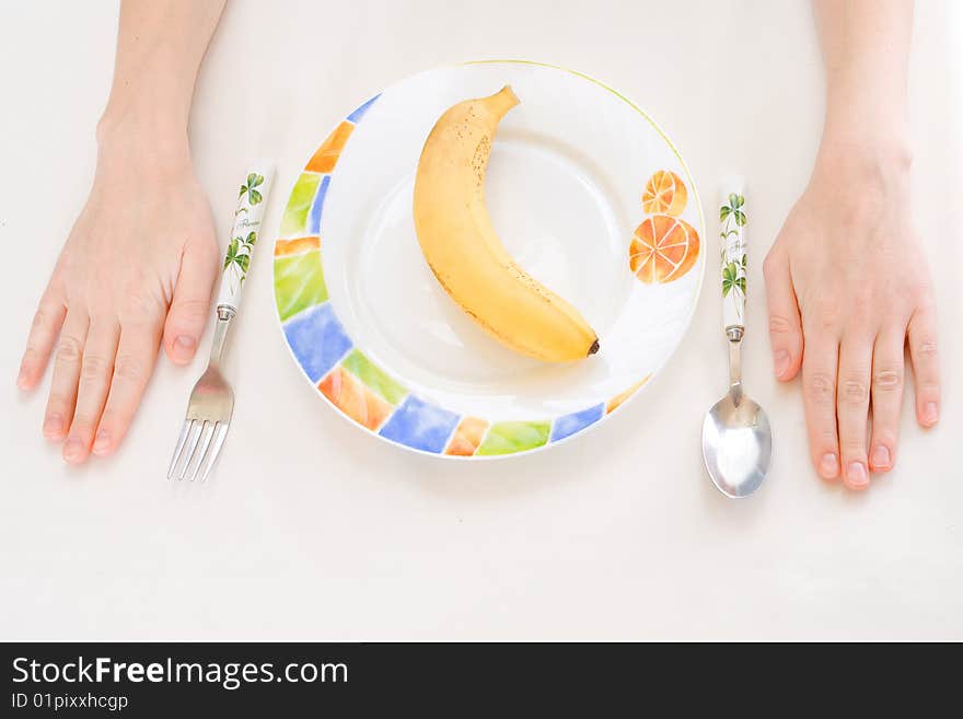 Banana on a plate, fork spoon hands