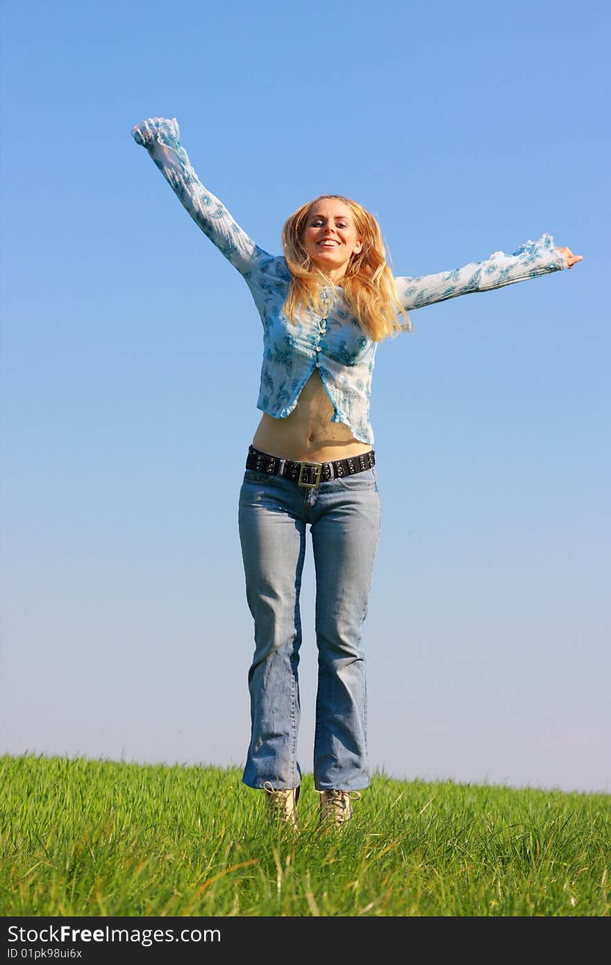 Woman jumping on green grass, blue sky in background. Woman jumping on green grass, blue sky in background