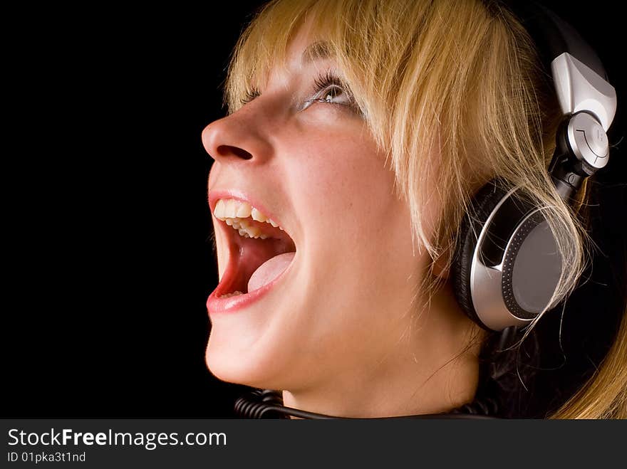 Portrait of a young girl with headphones
on a black background. Portrait of a young girl with headphones
on a black background