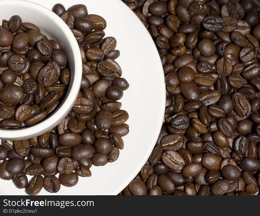 White coffee cup stacked with whole coffee beans. White coffee cup stacked with whole coffee beans