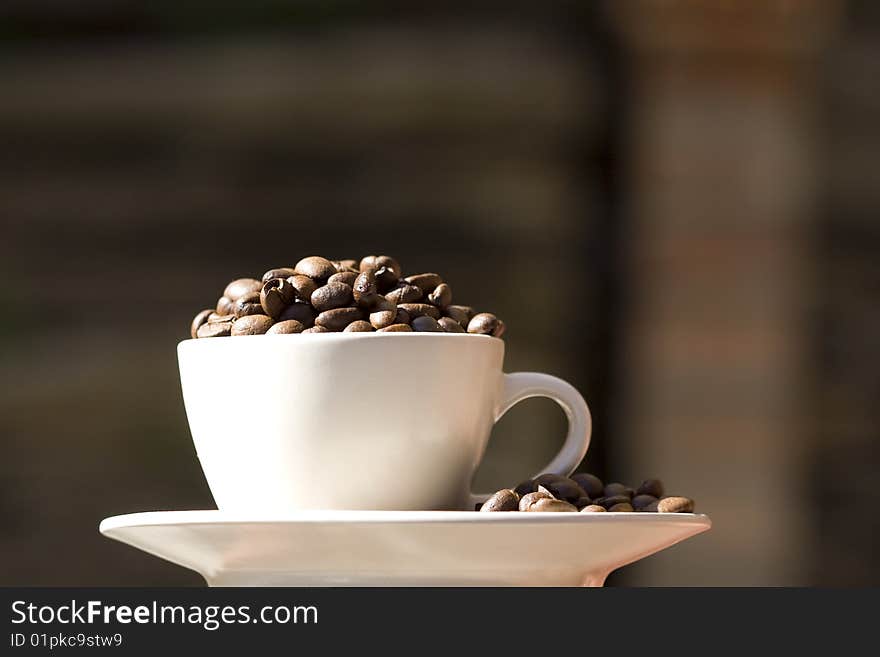 Photo of a coffe cup stacked with whole coffee beans - blur background. Photo of a coffe cup stacked with whole coffee beans - blur background