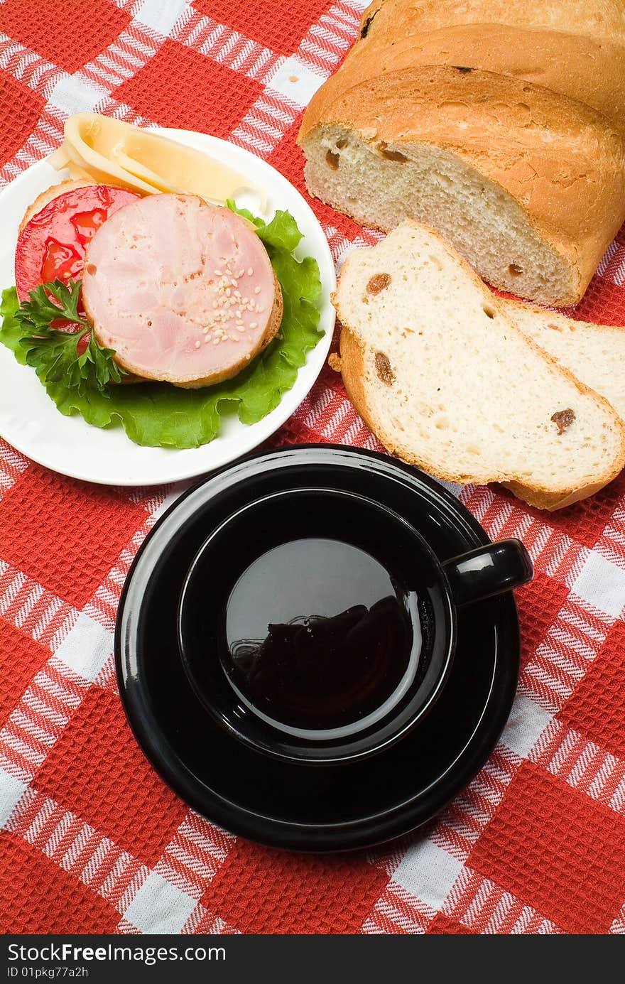 Bread, black cup of tea on a checked tablecloth